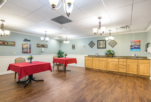 A spacious dining area featuring tables with red tablecloths and warm wooden accents.