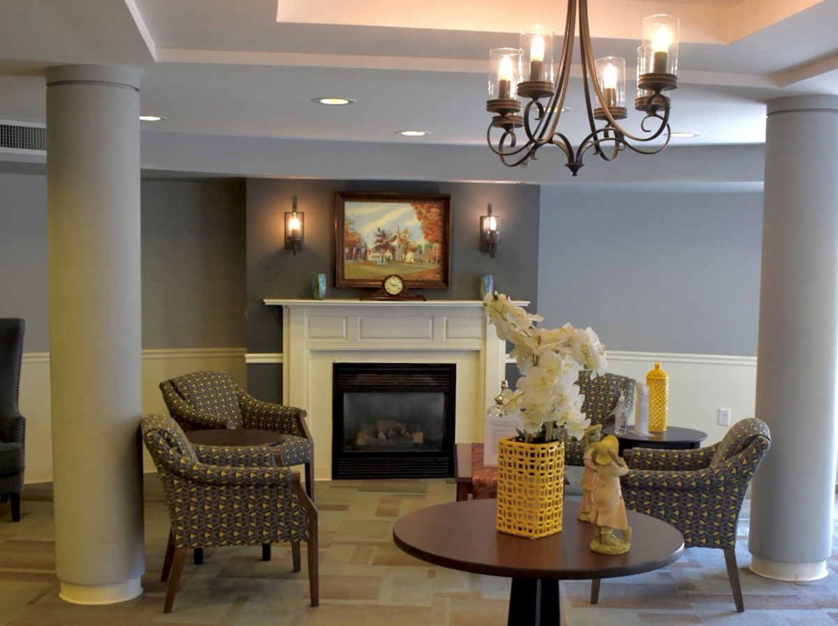 A cozy living room with a fireplace, elegant chandelier, and comfortable seating arrangement.