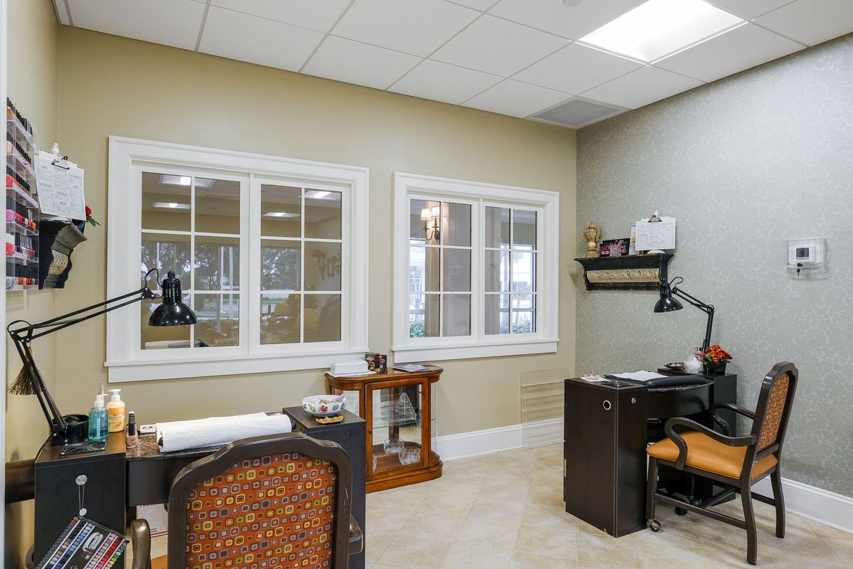 A tidy office space with a desk and chairs, featuring large windows.