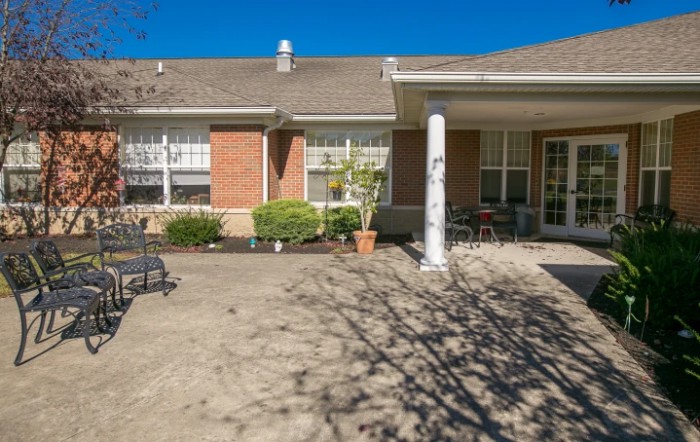 A sunny view of a house with a brick exterior and a spacious patio area.