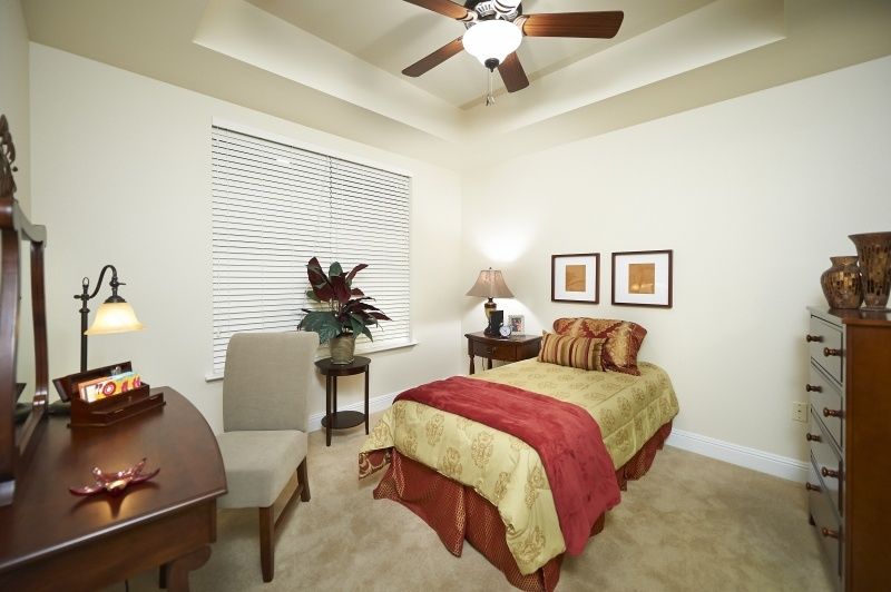 A cozy bedroom featuring a single bed with colorful bedding, a ceiling fan, and elegant decor.
