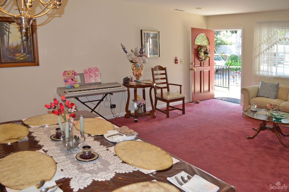 A cozy dining room with a set table and natural light streaming through the doorway.