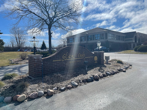 Entrance signage with a modern building in the background under a partly cloudy sky.