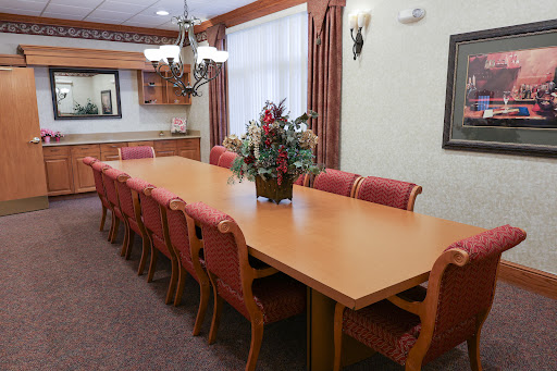 A well-furnished conference room featuring a long wooden table and comfortable chairs, ideal for meetings.