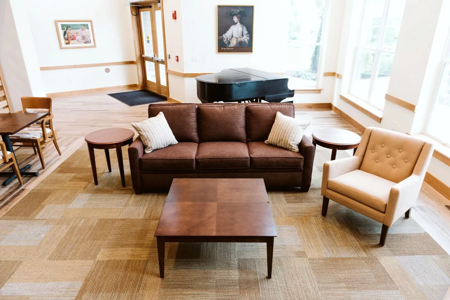 A cozy living area with a brown sofa, coffee table, and a piano in the background.