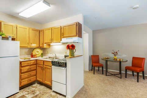 A cozy apartment kitchen with wooden cabinets and a small dining area.