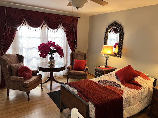 A cozy and elegantly decorated bedroom featuring warm red accents and inviting furniture.