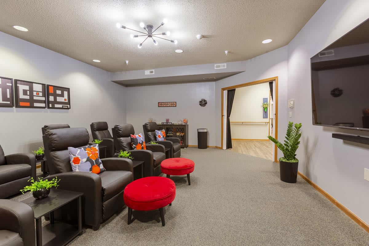 A cozy home theater room featuring plush recliners, bright red ottomans, and modern decor.