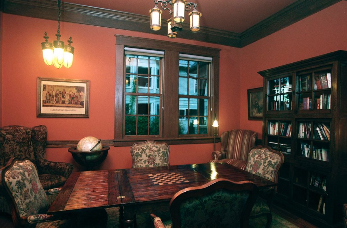 A cozy vintage study room with a chessboard on the table and bookshelves in the background.