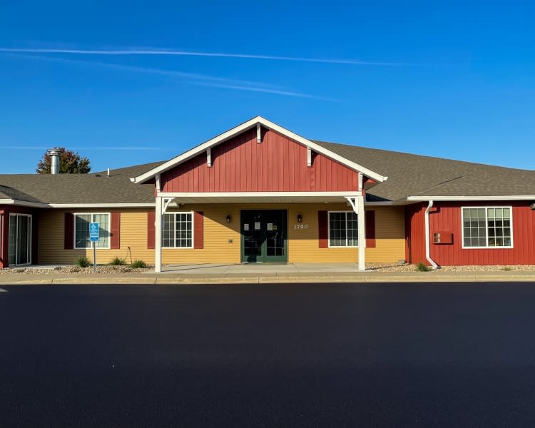 A single-story building with a red and beige facade under a clear blue sky.