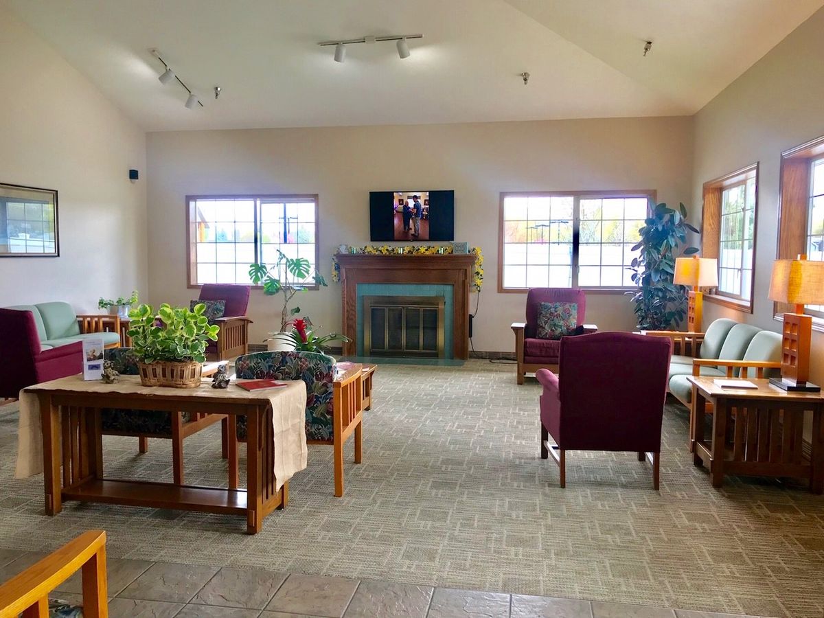 A cozy living room with comfortable seating, a fireplace, and plants by the windows.