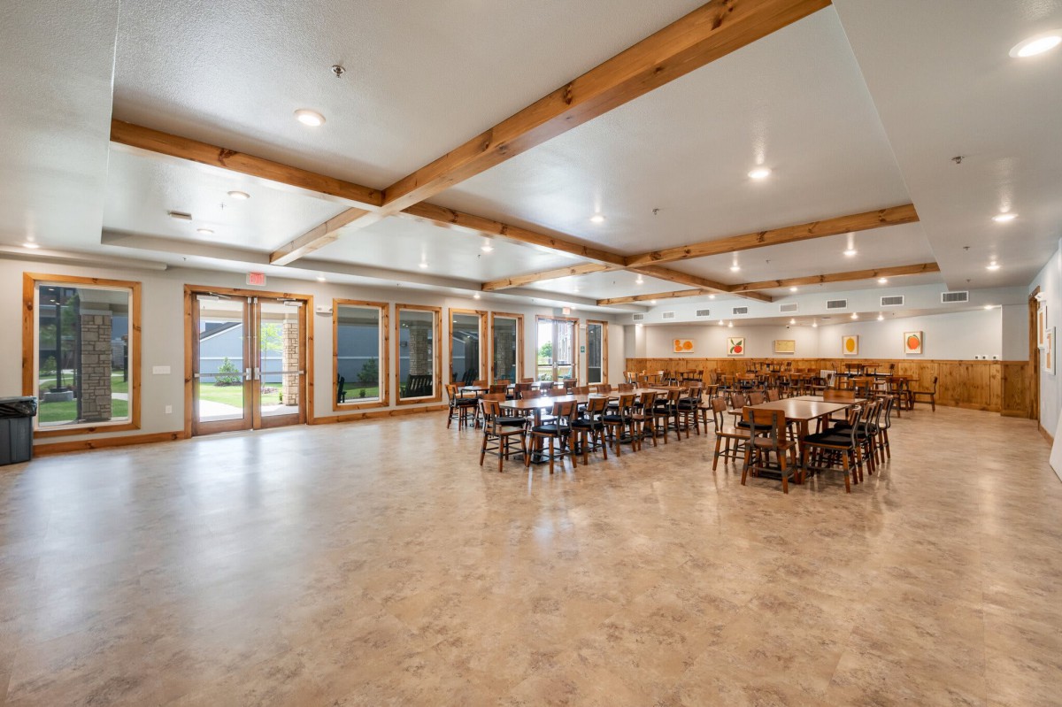 A spacious event venue featuring wooden beams and large windows that allow natural light to illuminate the dining area.
