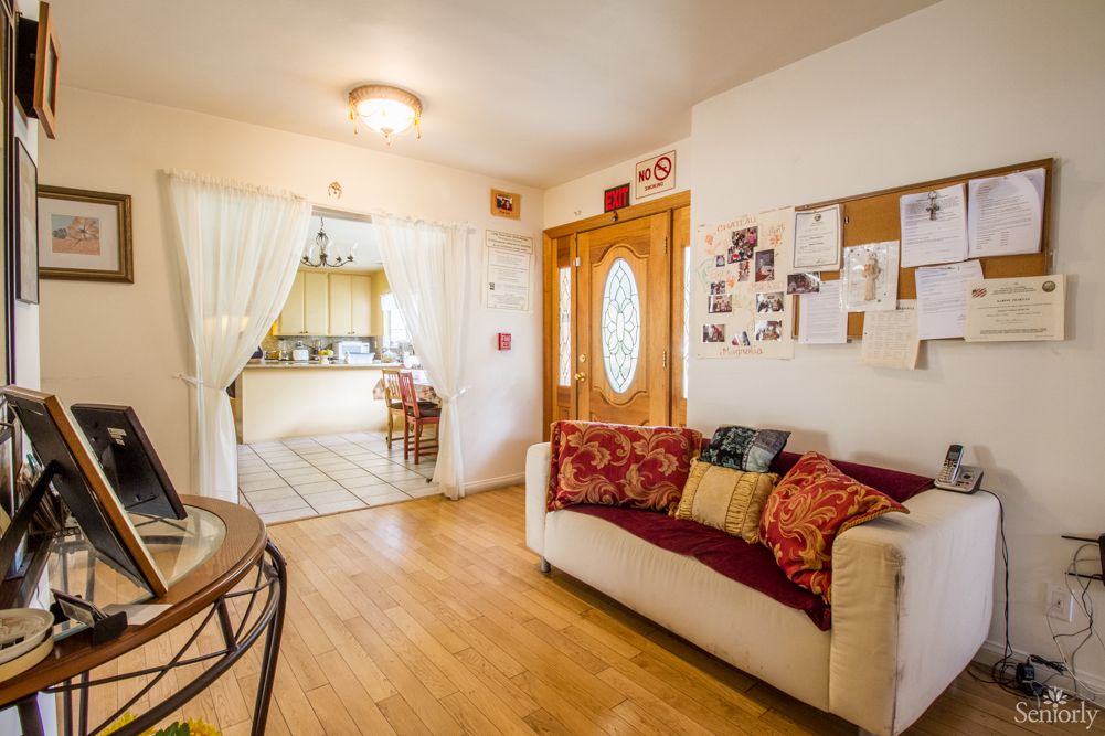 A cozy living room with a sofa, wooden flooring, and a view into the kitchen.