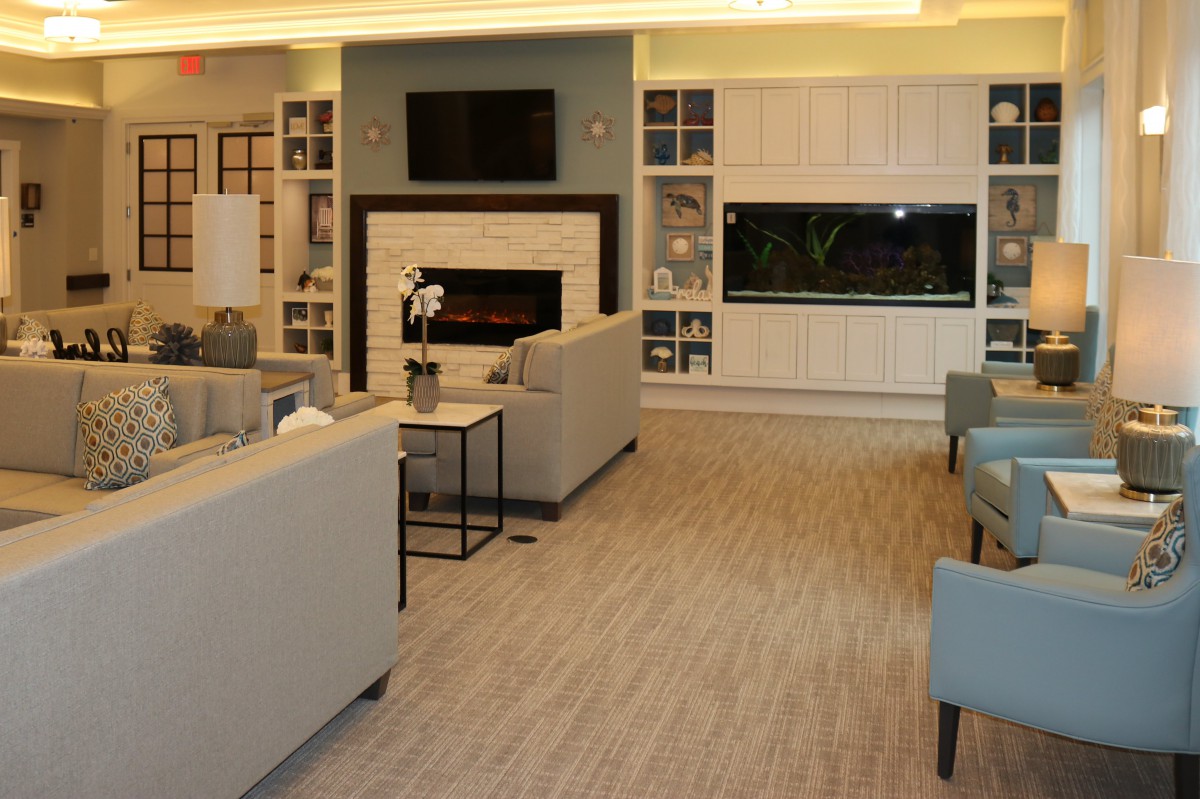 A modern living room with comfortable seating, a fireplace, a television, and a large aquarium.