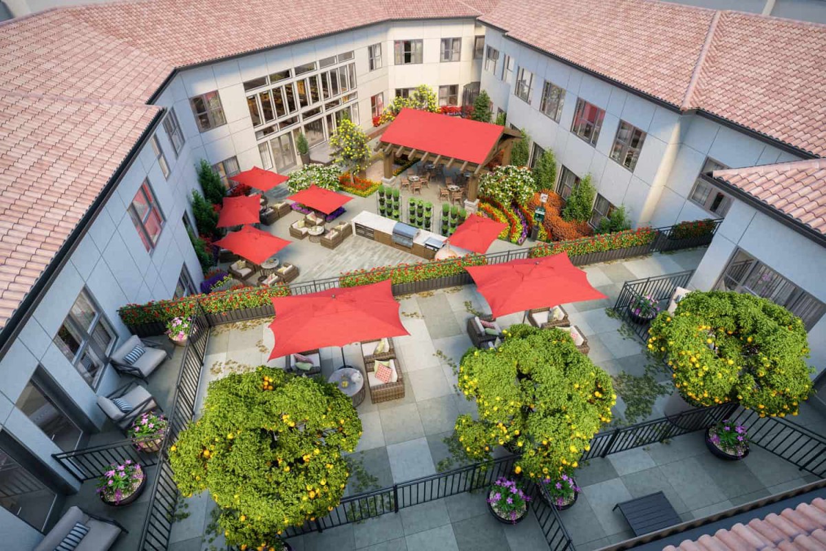 A beautifully landscaped courtyard featuring outdoor seating with red umbrellas.