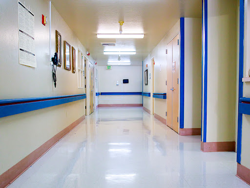 A clean and well-lit hallway in a hospital, featuring blue accents along the walls.