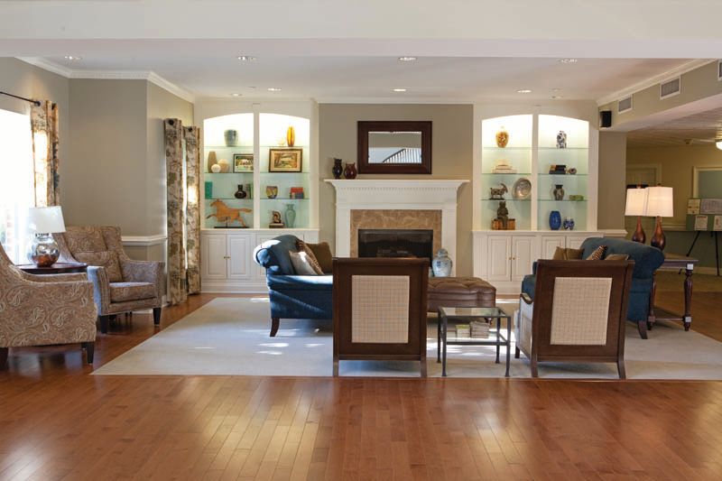 A cozy living room with a fireplace, elegant furniture, and decorative shelves.