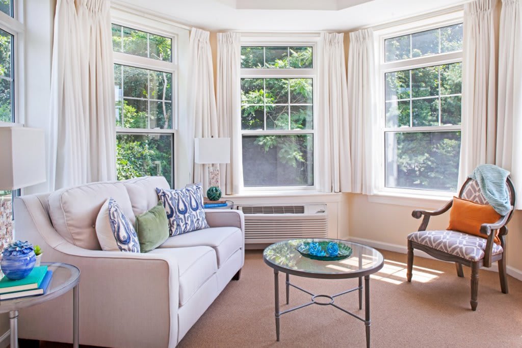 A bright and cozy living room with bay windows and comfortable seating.