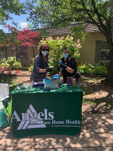 Two healthcare workers at an outdoor event promoting home health services.