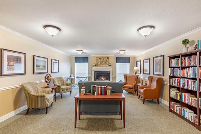 A cozy seating area with a central fireplace, featuring comfortable chairs and various decorations.
