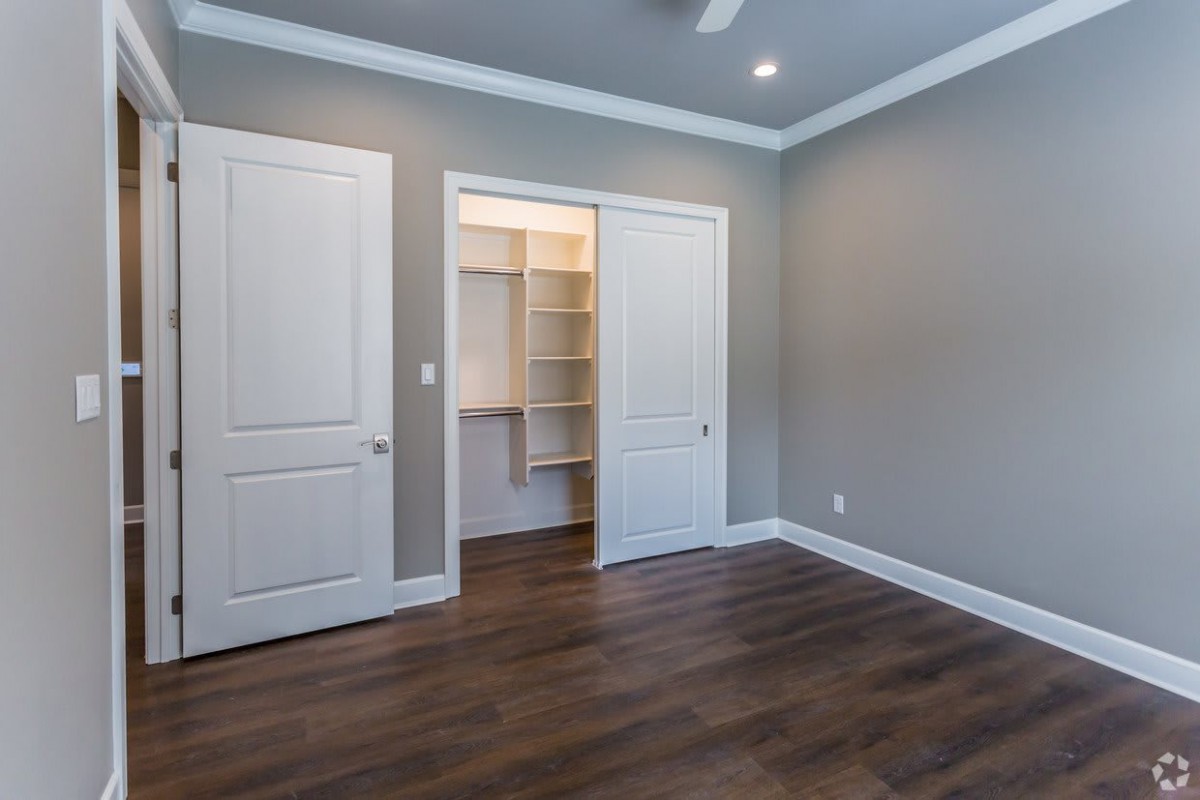 An empty room with hardwood floors and a walk-in closet.
