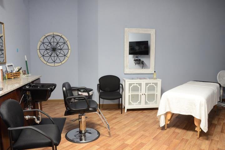 A modern salon interior with styling chairs, a mirror, and a massage table.
