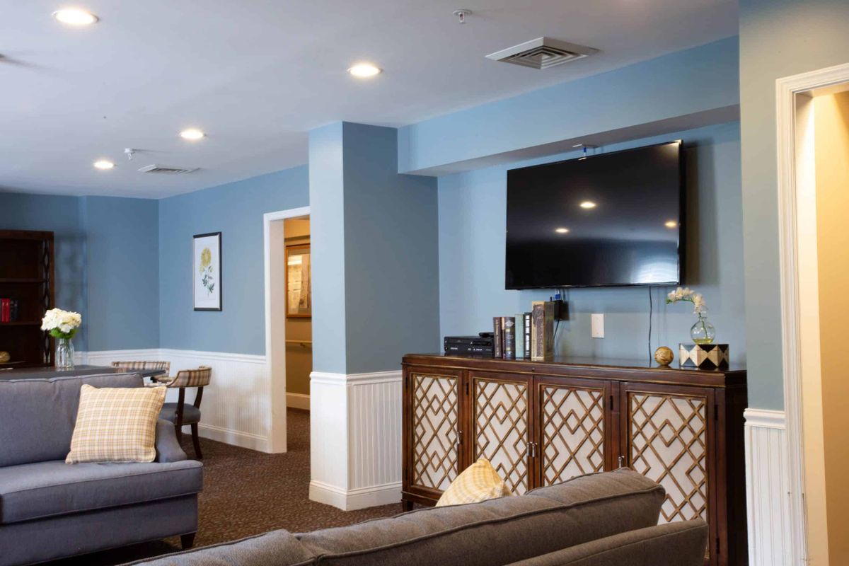 A cozy and modern living room with blue walls, featuring a large television and stylish furniture.
