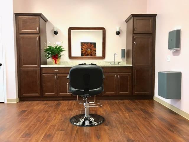 A modern hair salon setup with a central chair and stylish cabinetry.