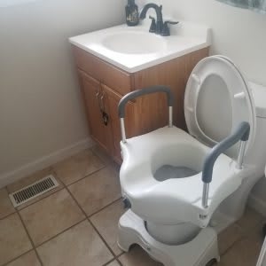 A bathroom featuring a child toilet seat over the regular toilet, next to a sink.