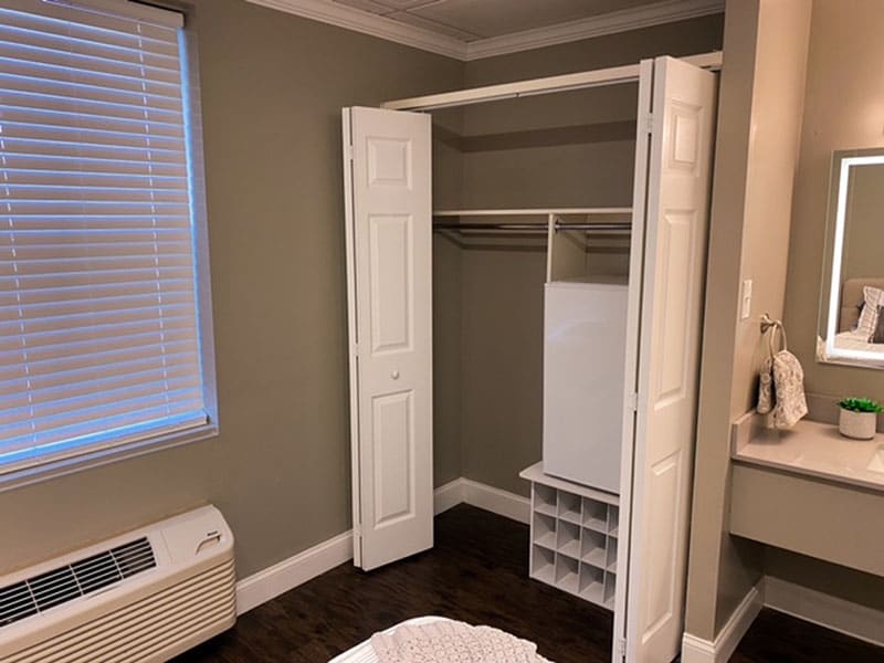 An empty closet with open doors and a shelving unit inside.