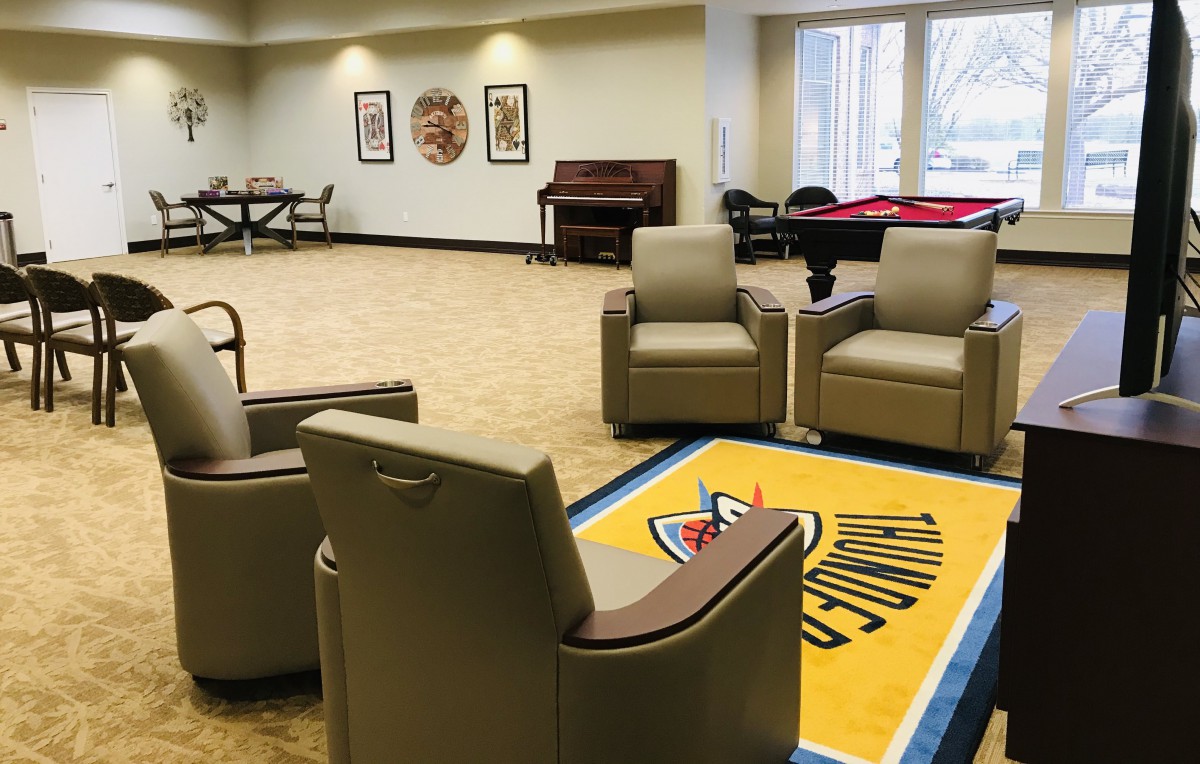 A spacious lounge area featuring comfortable seating, a pool table, and a piano for recreation.