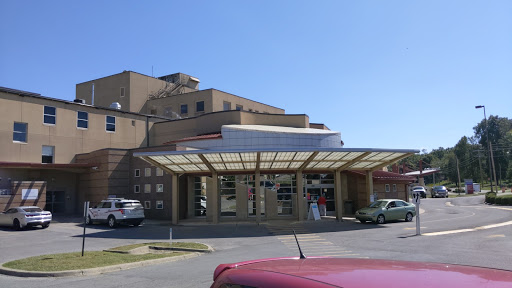 A view of a hospital building with a covered entrance on a clear day.