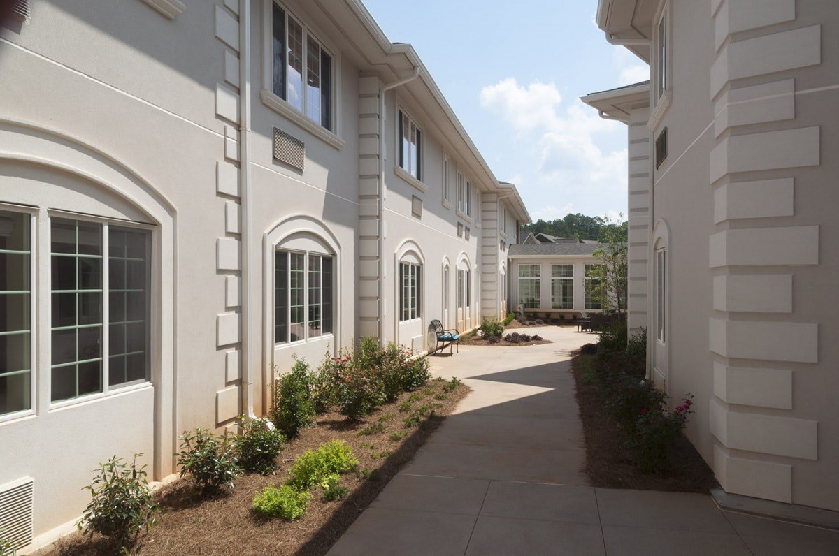 A sunny view of an exterior walkway between two buildings with landscaped areas.