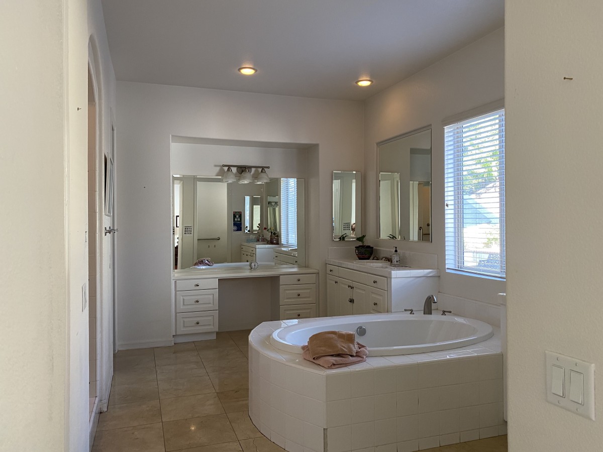 A modern bathroom with a bathtub and a cat resting on it.