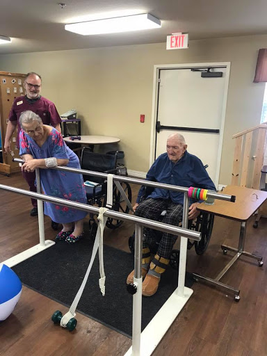 Elderly individuals participating in a rehabilitation session with assistance from staff.