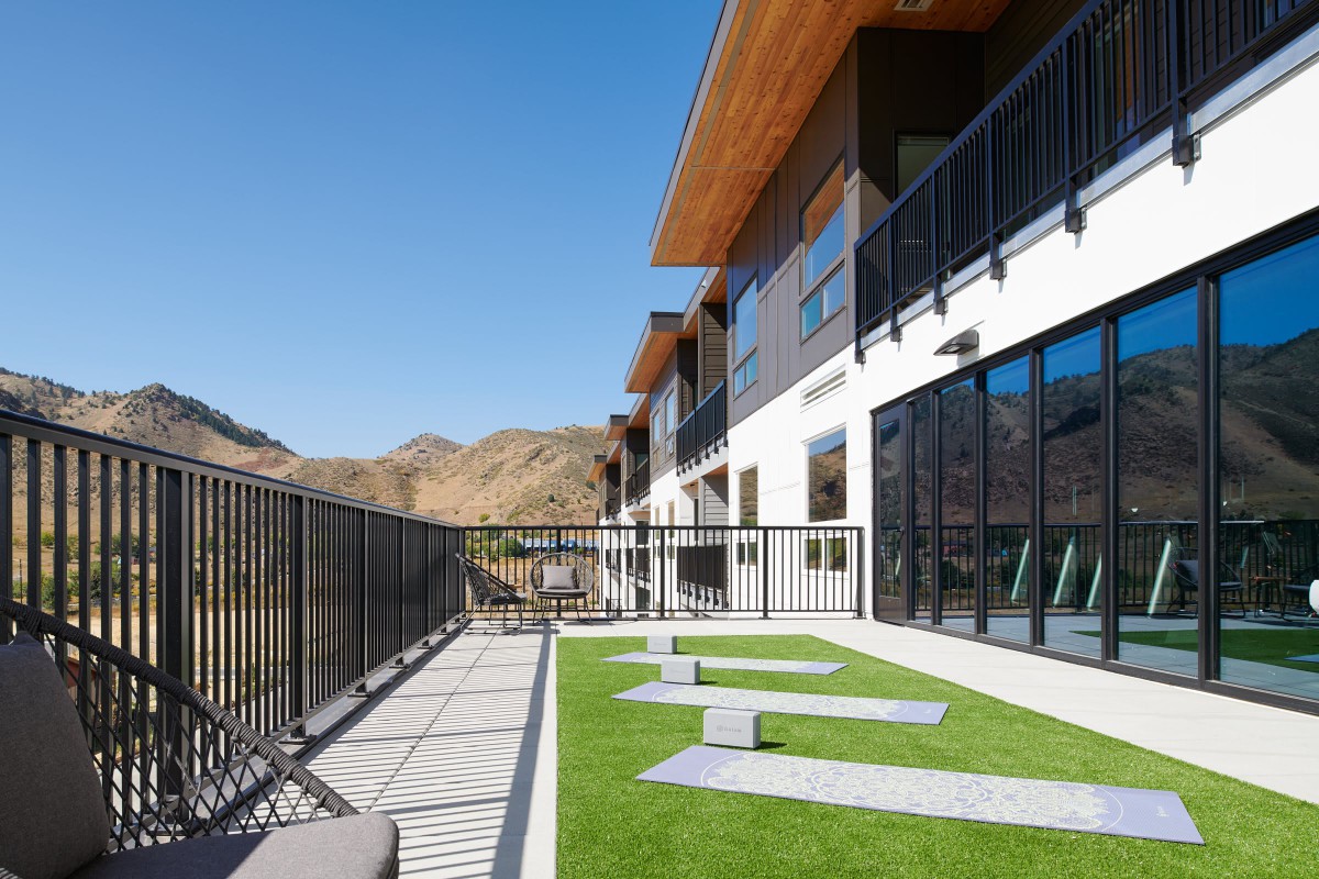 A modern building with a spacious balcony overlooking a mountainous landscape.