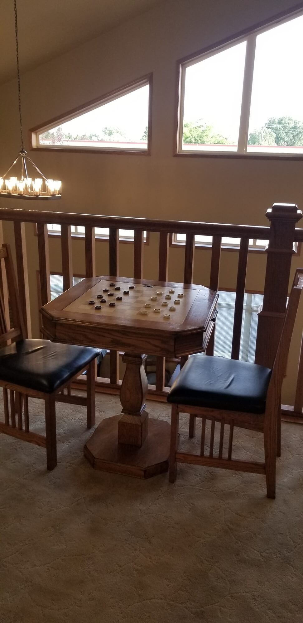 A cozy indoor setup with a wooden game table and chairs overlooking a balcony.
