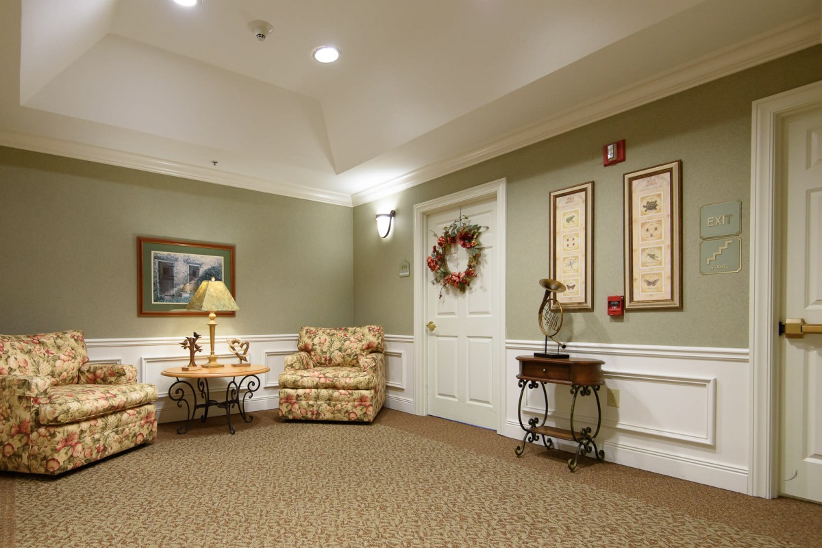 A cozy living room with a floral sofa, decorative lamp, and framed artwork on the wall.