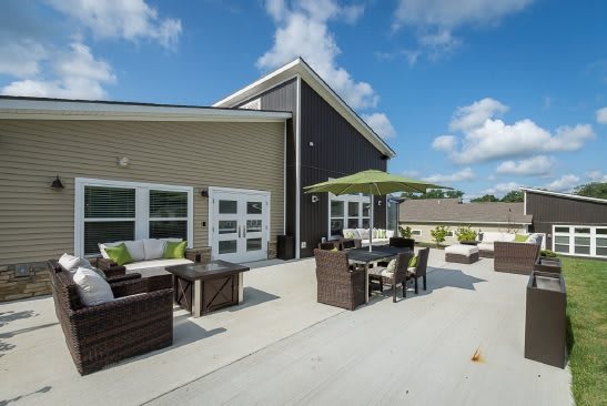 A modern outdoor patio with comfortable seating and a large umbrella.