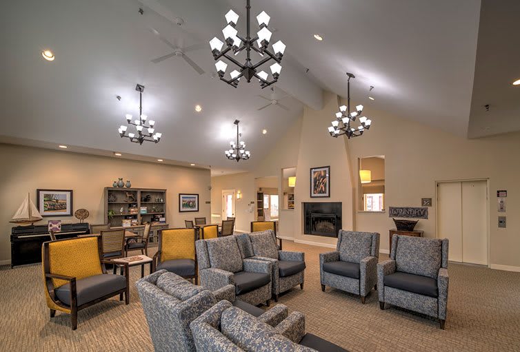 A spacious and elegant living room with cozy seating, chandeliers, and a fireplace.