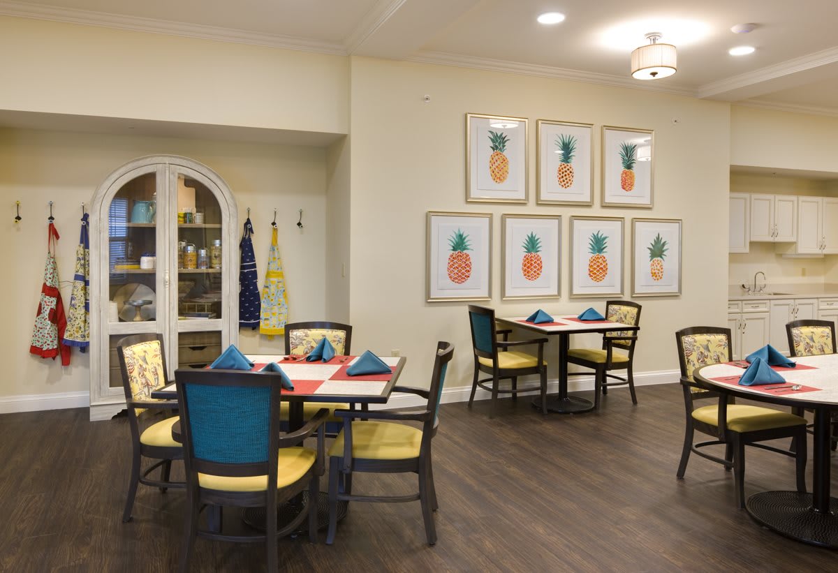 A cozy dining area featuring tables and chairs, decorated with artwork of pineapples on the wall.