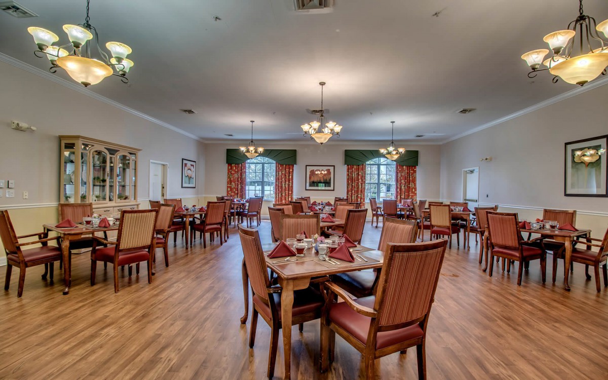 Spacious dining room with elegant chandeliers and wooden flooring.