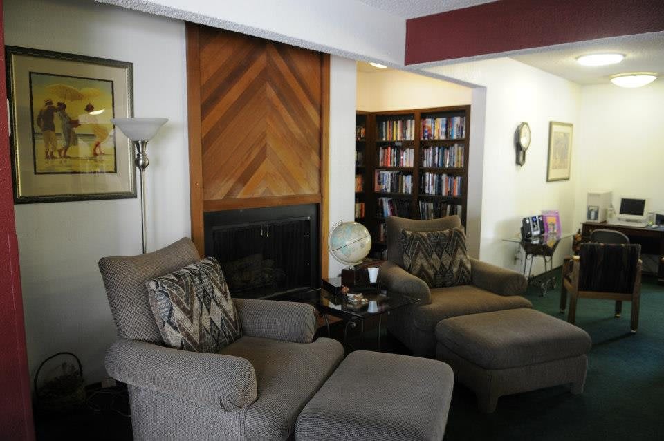 A cozy living room featuring two comfortable chairs, a bookshelf filled with books, and a small globe on the side table.