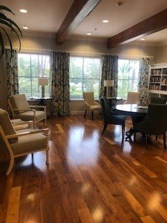 A cozy living room with comfortable seating, large windows, and a wooden floor.