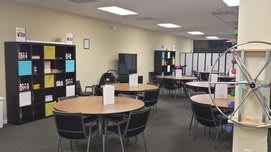 A spacious office area with round tables and chairs arranged for meetings.