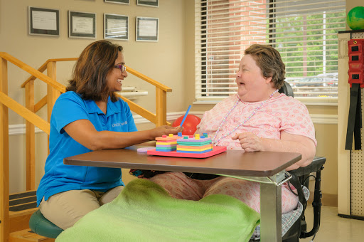 A caregiver engages in a joyful interaction with a patient during a therapeutic activity.