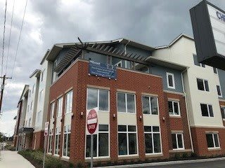 A multi-story building with visible roof damage under an overcast sky.