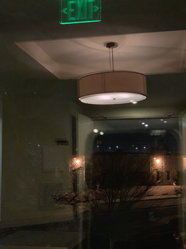 A modern interior with a prominent ceiling light fixture reflecting off a glass surface.