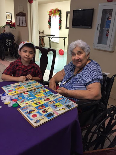 A young boy and an elderly woman enjoying a board game together, sharing smiles and companionship.