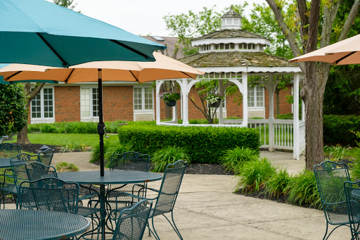 A peaceful outdoor garden area featuring a gazebo, patio furniture, and colorful umbrellas.